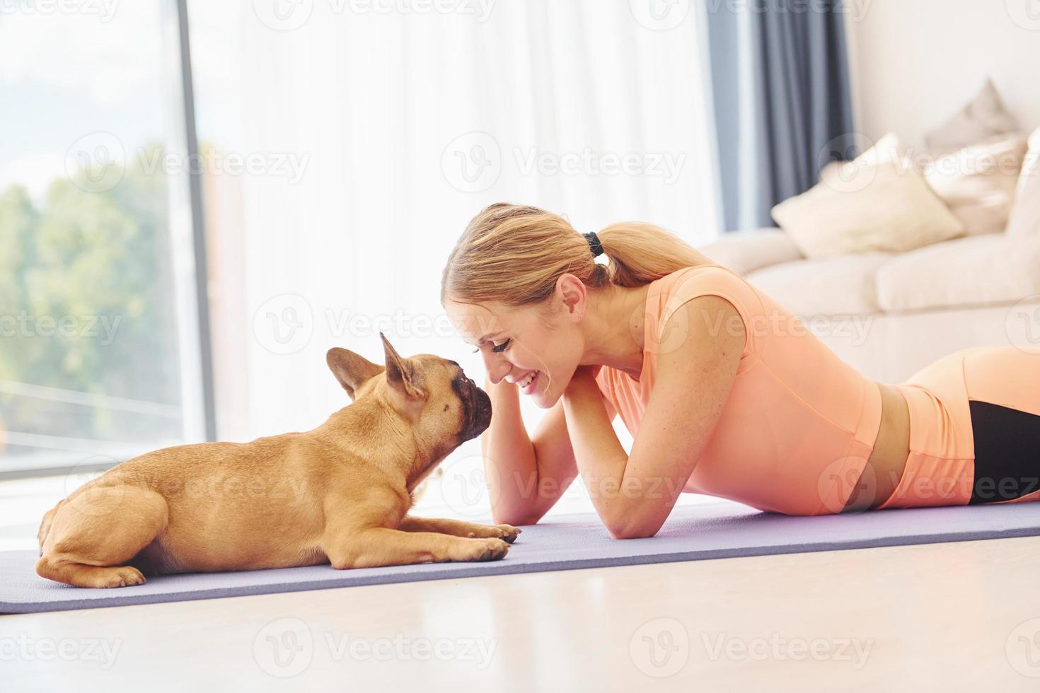 Laying down on the mat. Woman with pug dog is at home at daytime photo