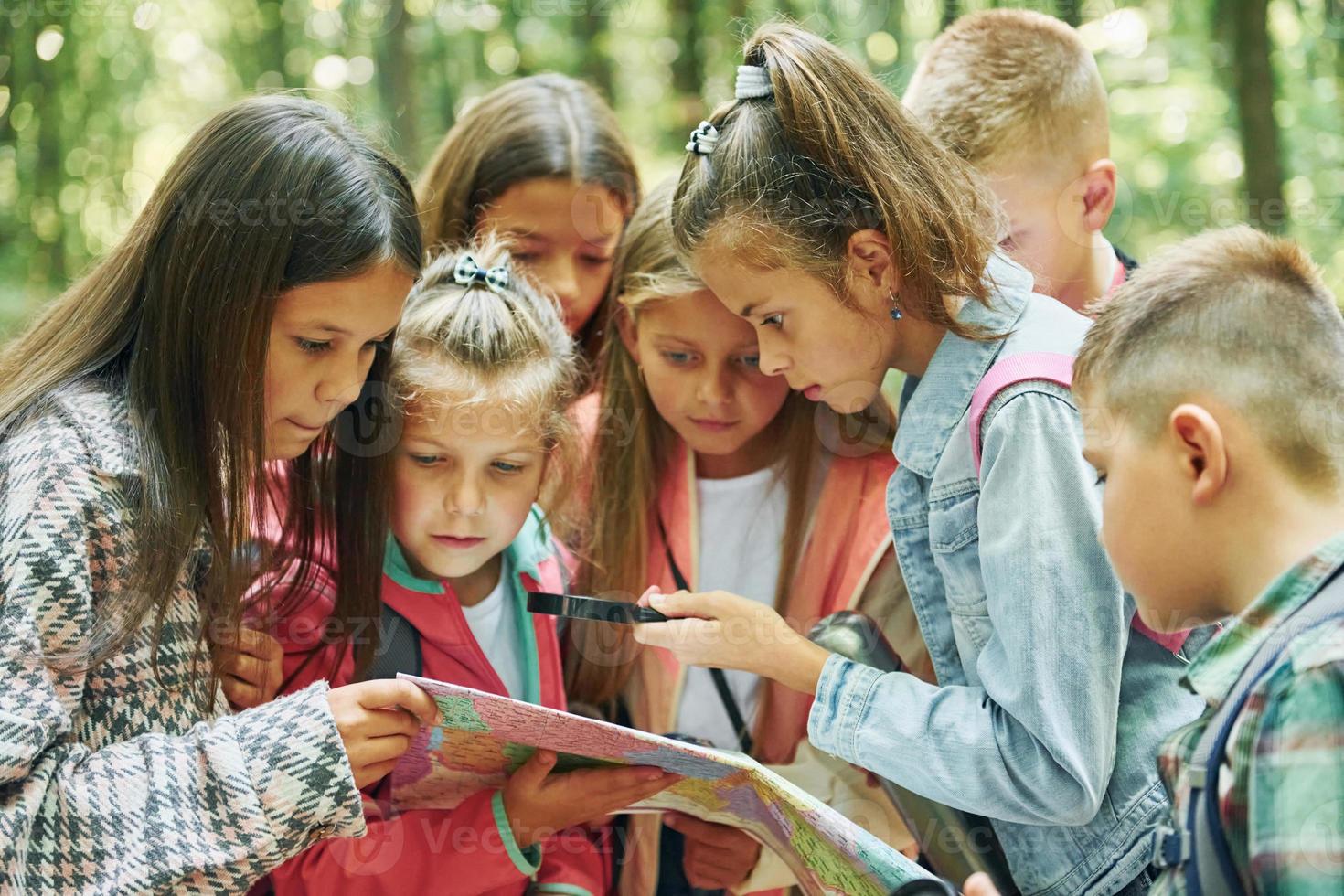 With map. Kids in green forest at summer daytime together photo