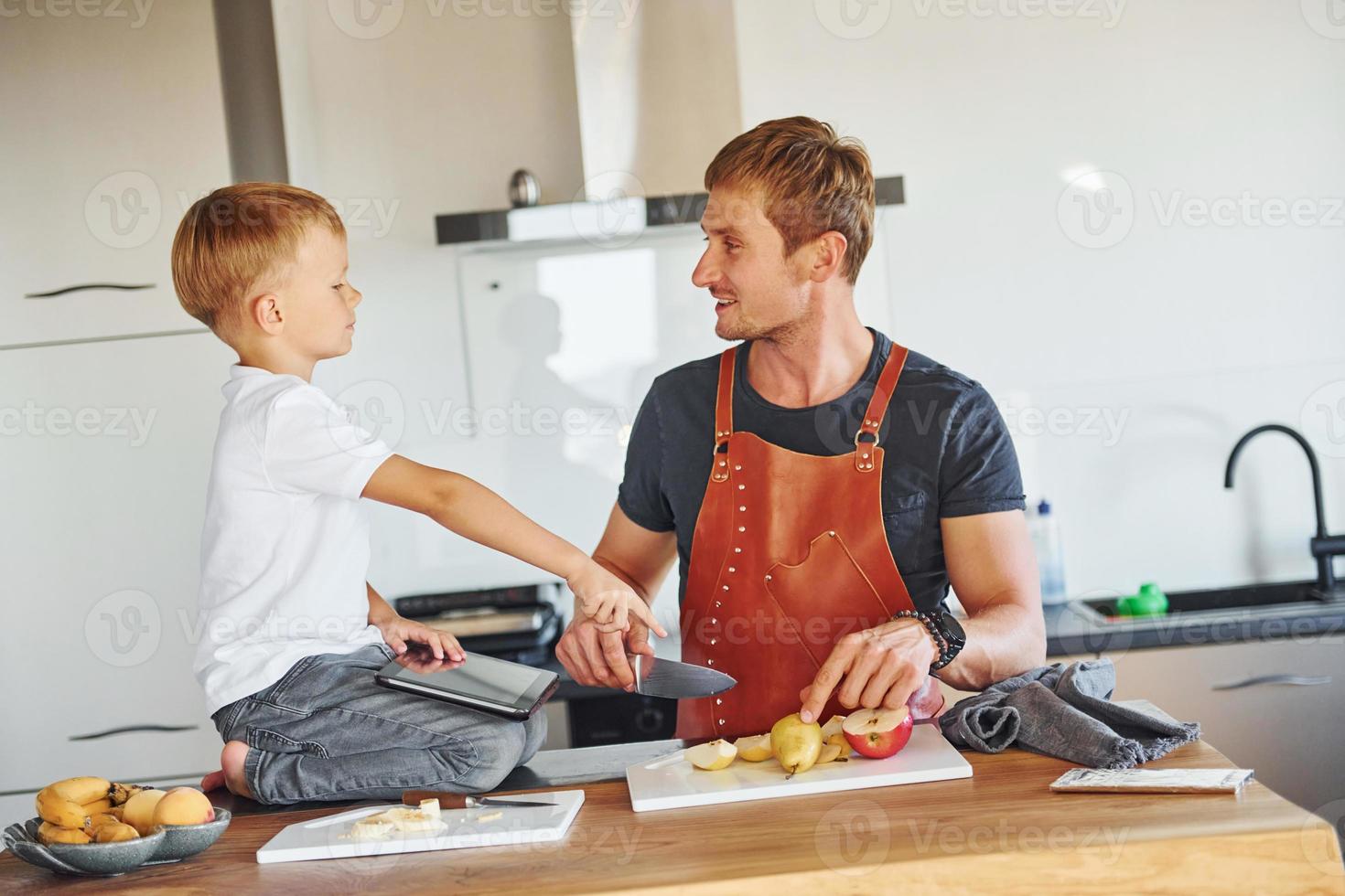 Fruits is on the table. Father and son is indoors at home together photo
