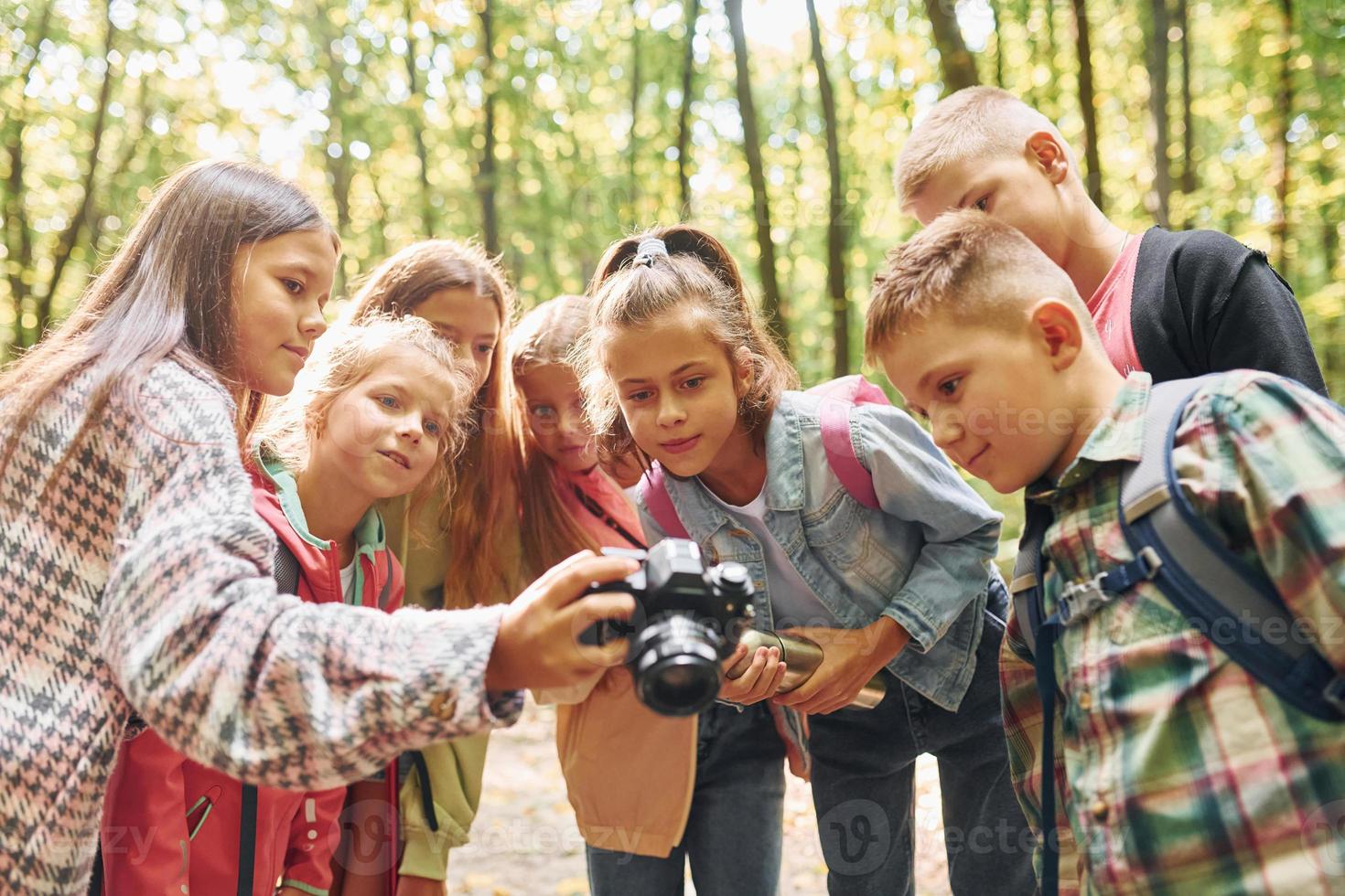 Front view. Kids in green forest at summer daytime together photo