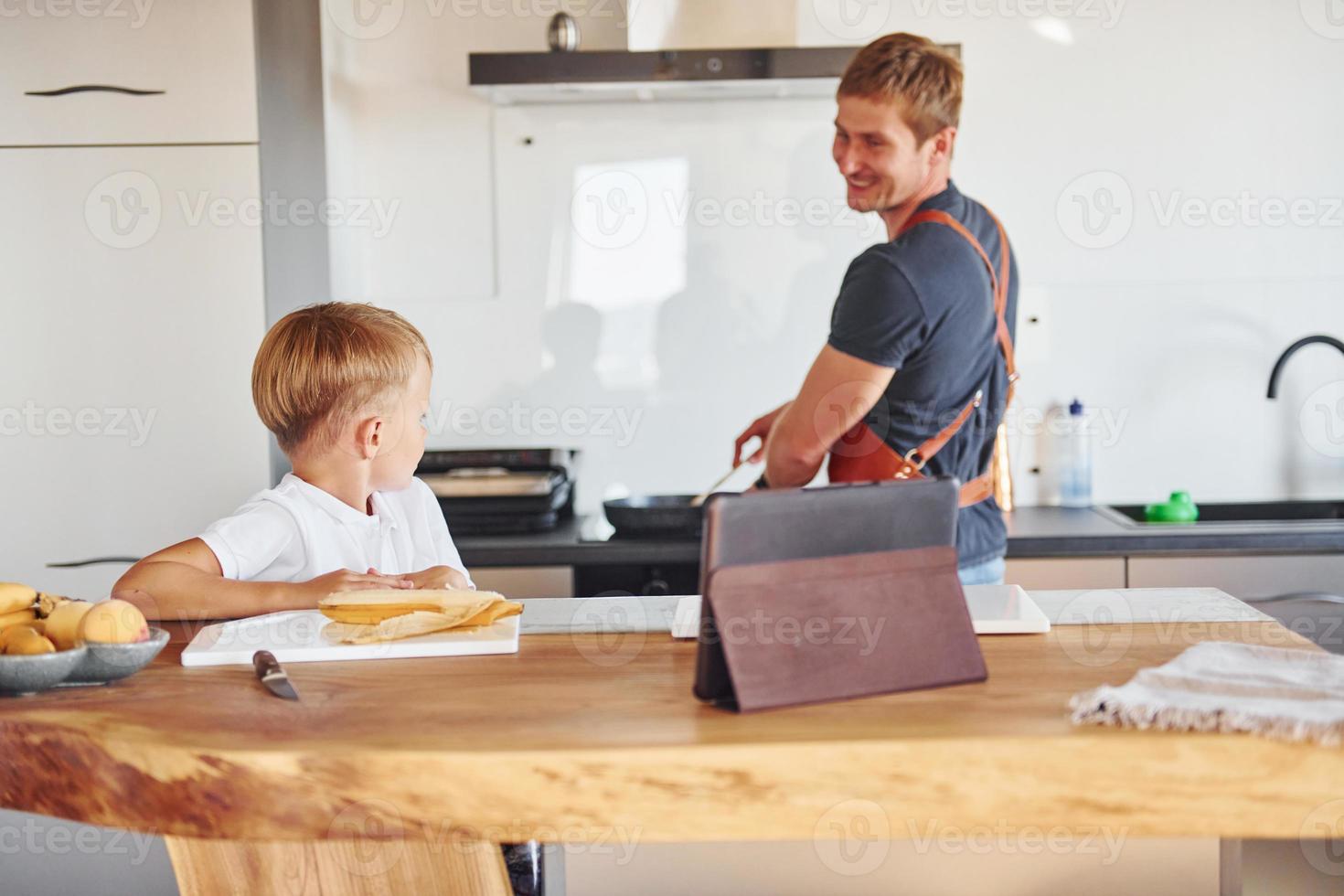 usando tableta para aprender a cocinar. padre e hijo están juntos en casa en el interior foto