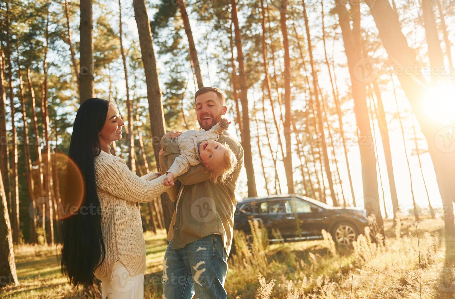 descanso de fin de semana. feliz familia de padre, madre e hija pequeña está en el bosque foto