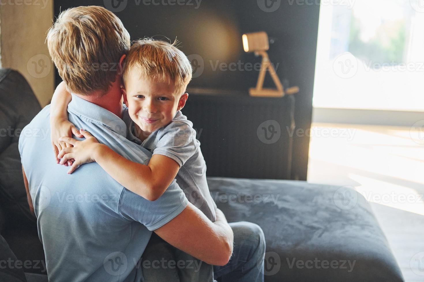 Boy embracing his parent. Father and son is indoors at home together photo