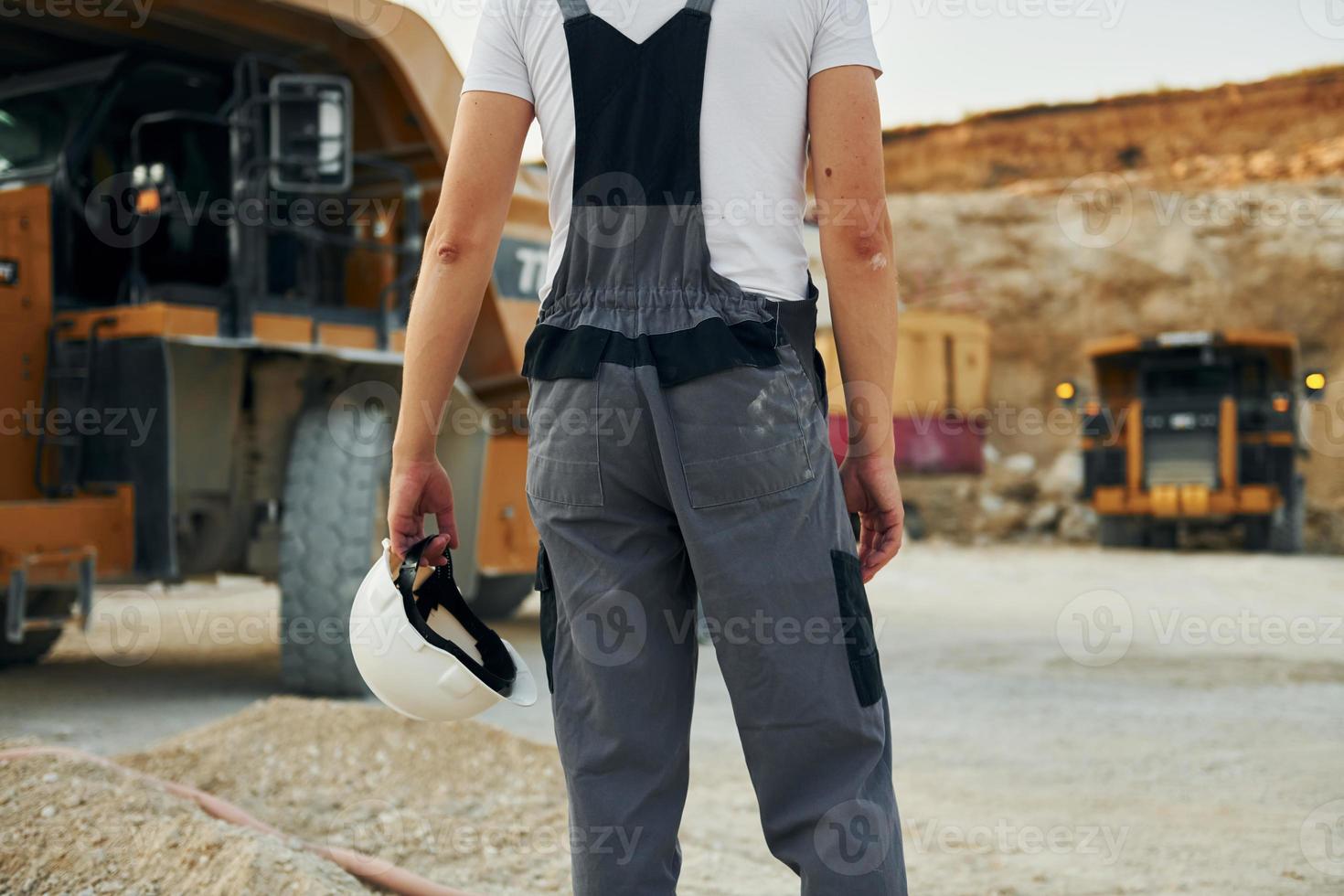 vista trasera. el trabajador con uniforme profesional está en el pozo de préstamo durante el día foto