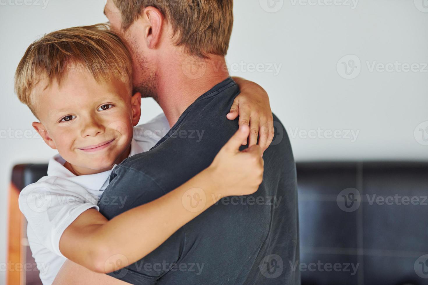 Embracing each other. Father and son is indoors at home together photo