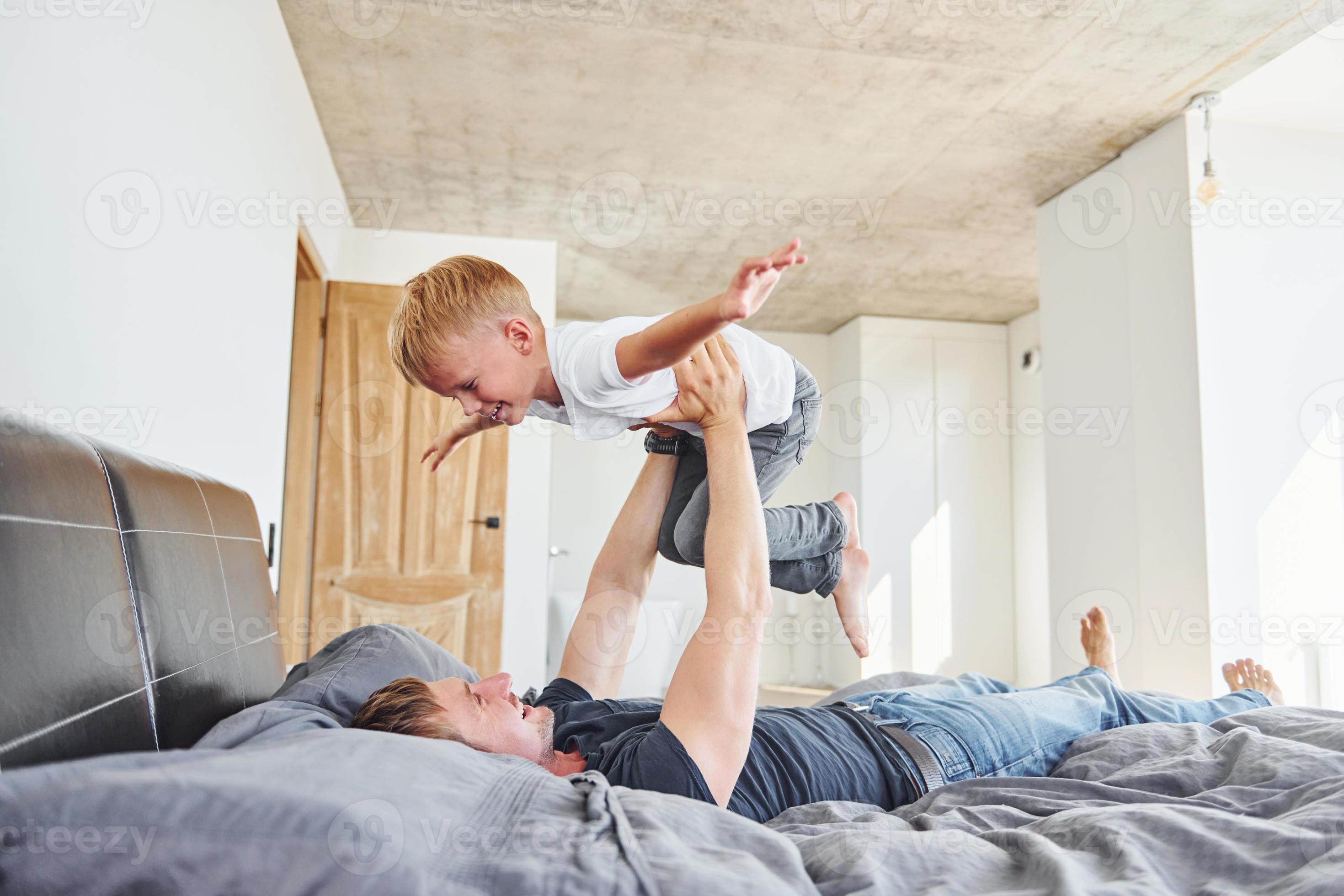 Laying down on the bed. Father and son is indoors at home together 15460704 Stock Photo at Vecteezy