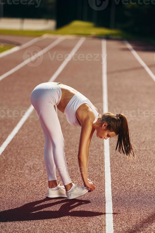 Stretching exercises. Young woman in sportive clothes is doing fitness outdoors photo