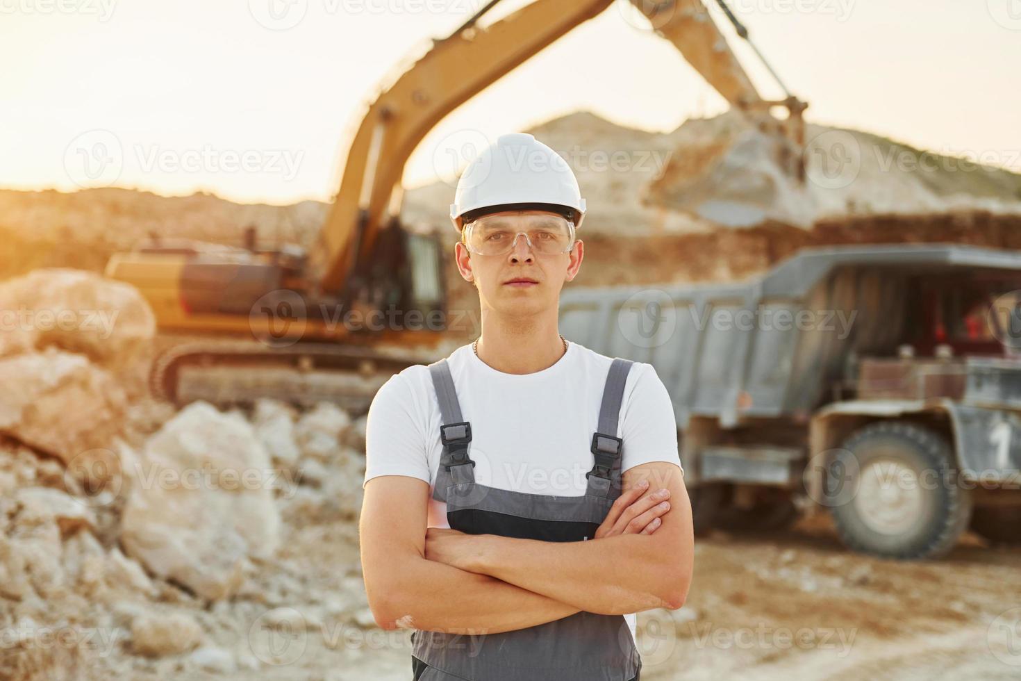 Standing with arms crossed. Worker in professional uniform is on the borrow pit at daytime photo
