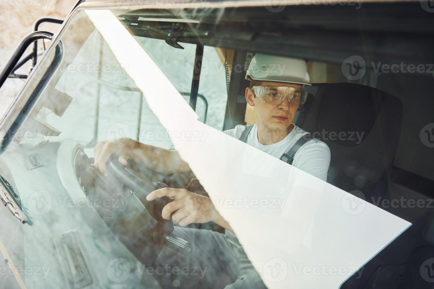 Driver is at work. Man in professional uniform is on the borrow pit at daytime photo