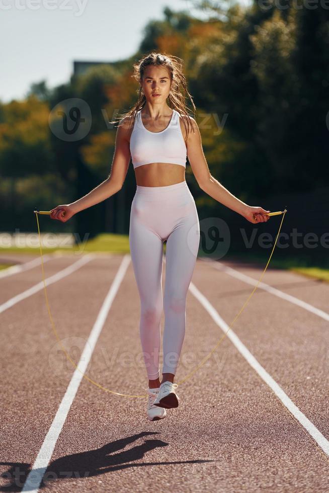 saltando en la pista de atletismo. mujer joven en ropa deportiva está  haciendo ejercicio al aire libre 15461181 Foto de stock en Vecteezy