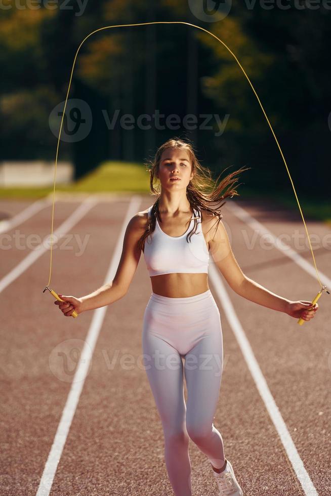 practicando con saltar la cuerda. mujer joven en ropa deportiva está haciendo ejercicio al aire libre foto