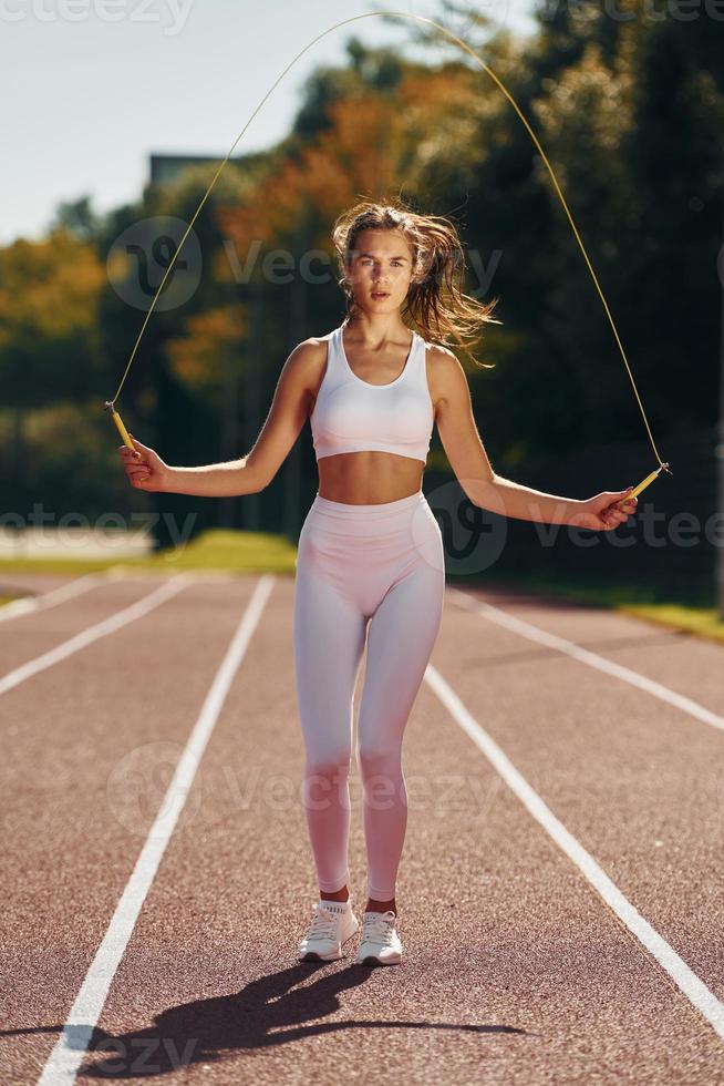 saltando en la pista de atletismo. mujer joven en ropa deportiva está haciendo ejercicio al aire libre foto