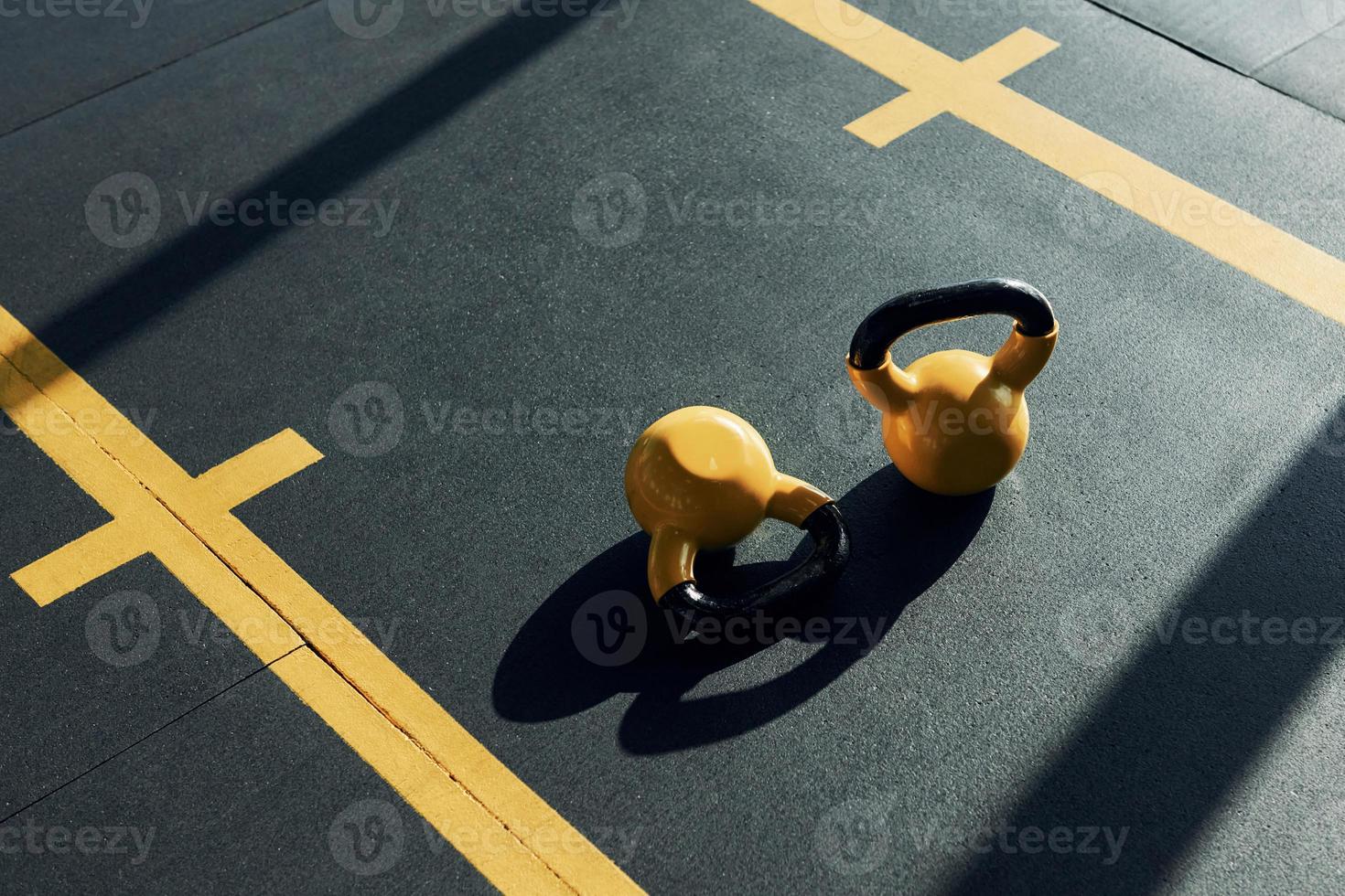 Weights painted in yellow color laying down on the ground in the gym photo