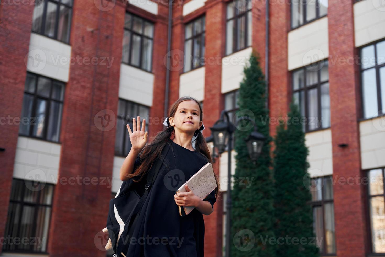 en uniforme de gala. la colegiala está afuera cerca del edificio de la escuela foto