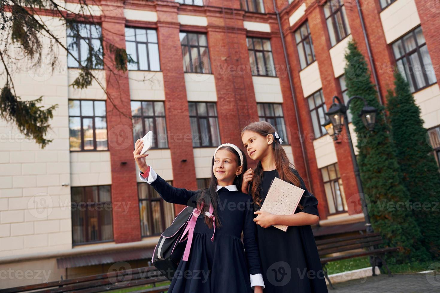 With books. Two schoolgirls is outside together near school building photo