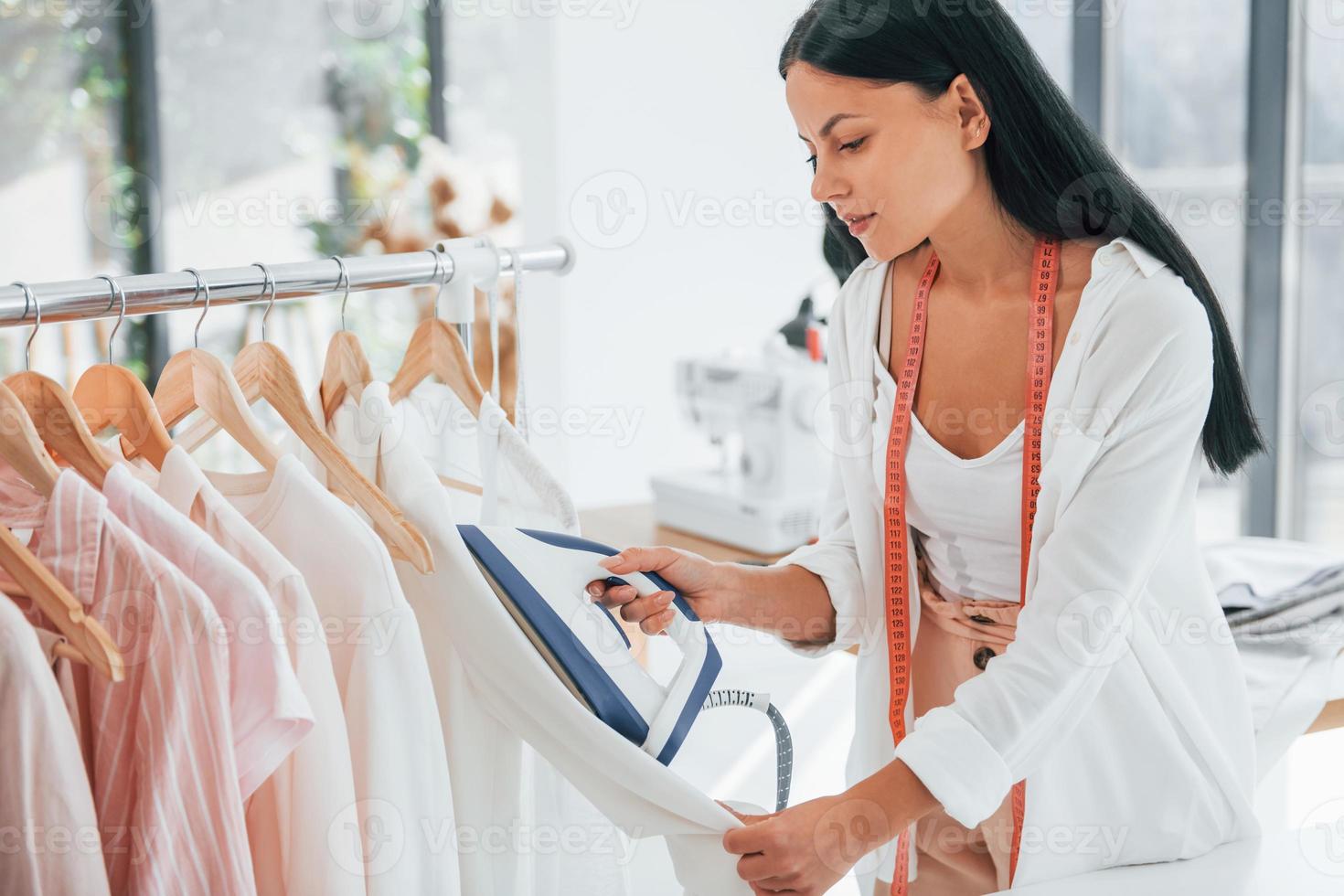 plancha la ropa. la costurera está en su oficina que está con ropa diferente foto