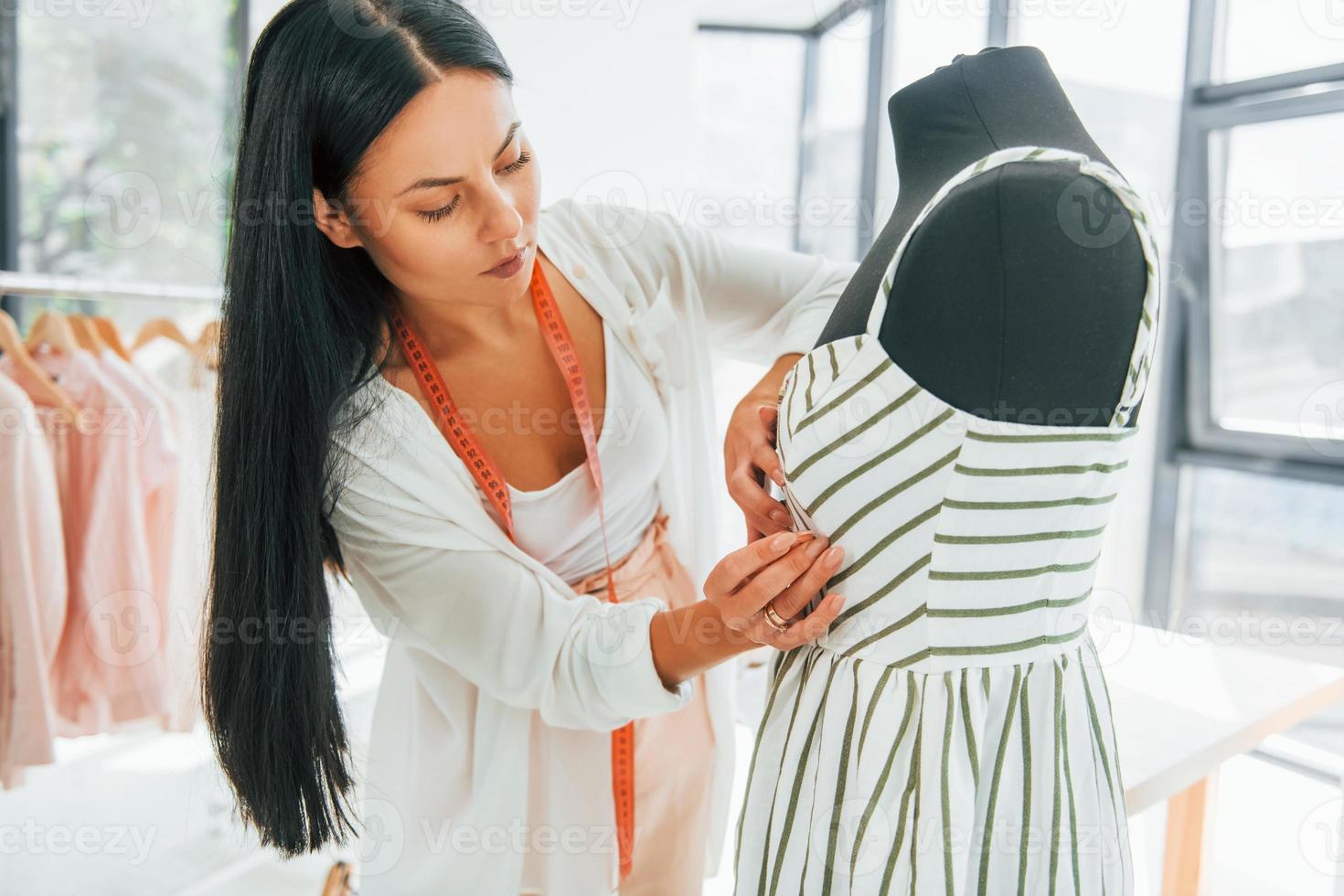 Measuring clothes. Seamstress is in her office photo