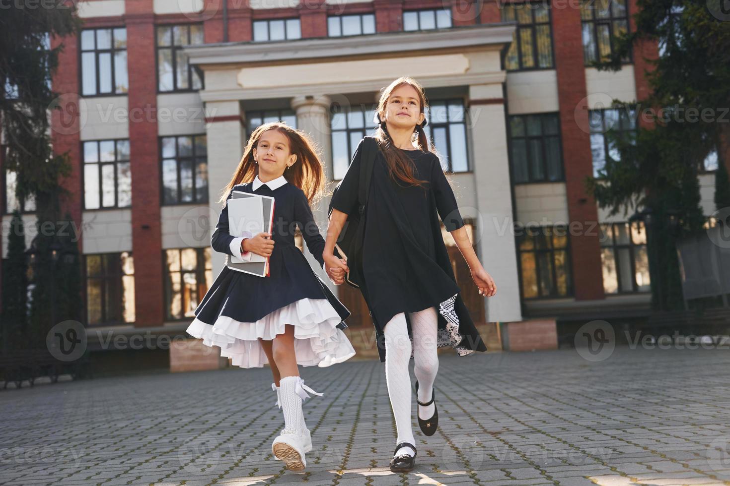 dos colegialas corren afuera juntas cerca del edificio de la escuela foto