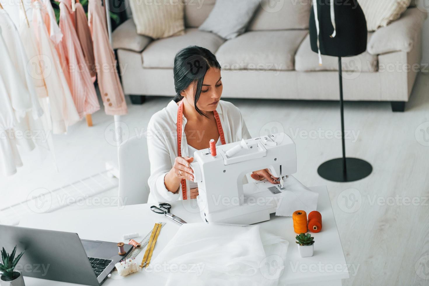 Máquina de coser profesional la costurera está en su oficina con ropa  diferente