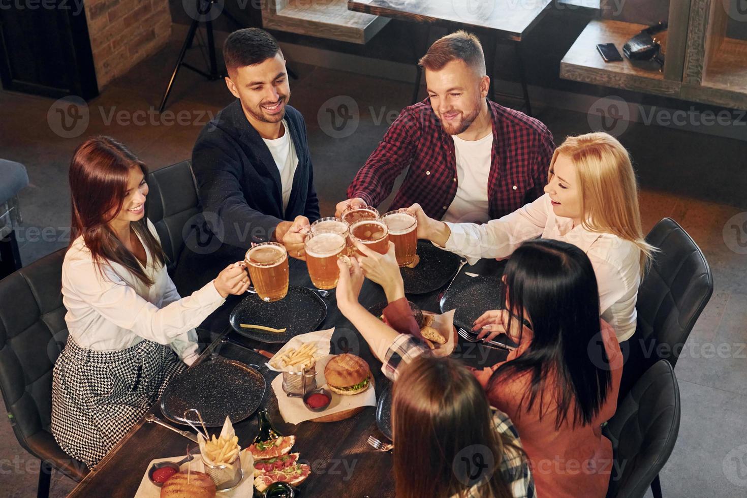 Free time. Group of young friends sitting together in bar with beer photo