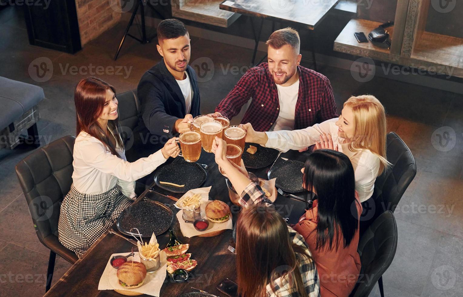 Free time. Group of young friends sitting together in bar with beer photo