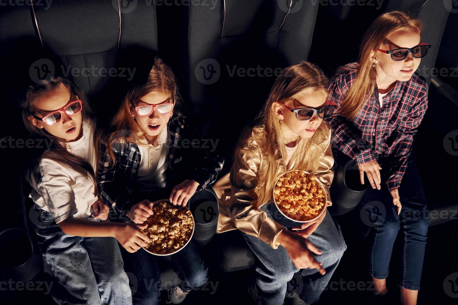 Top view. Group of kids sitting in cinema and watching movie together photo