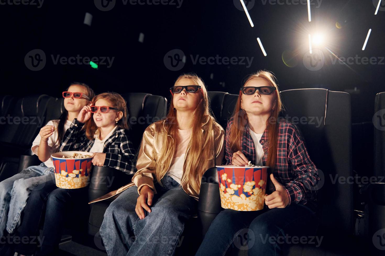 Facial expressions. Group of kids sitting in cinema and watching movie together photo