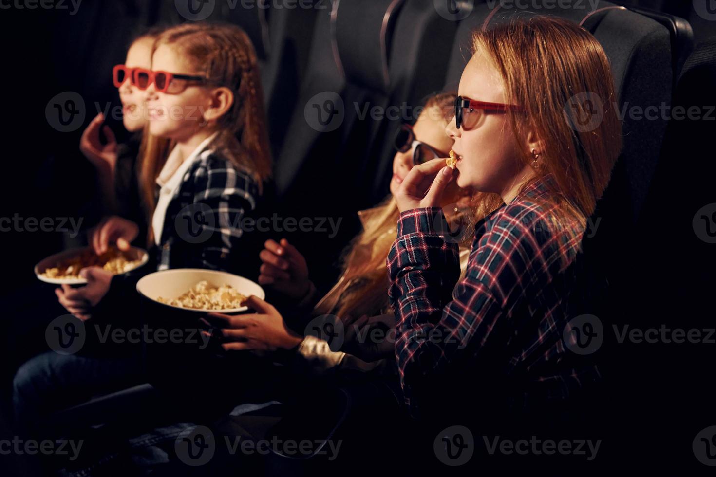 In 3D glasses. Group of kids sitting in cinema and watching movie together photo