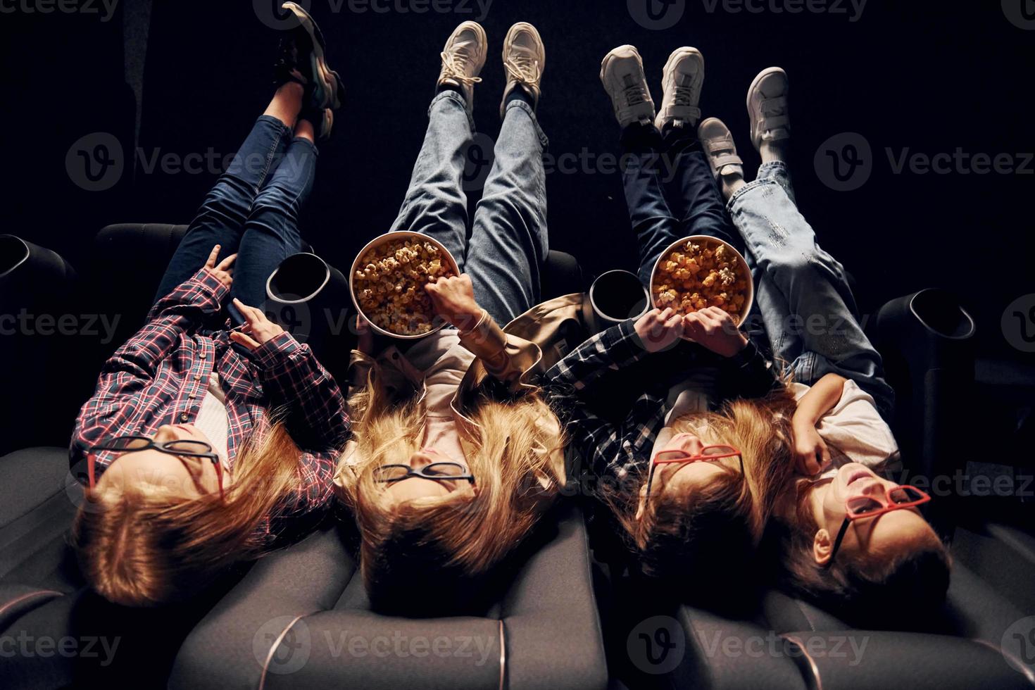 deliciosas palomitas de maíz. grupo de niños sentados en el cine y viendo películas juntos foto