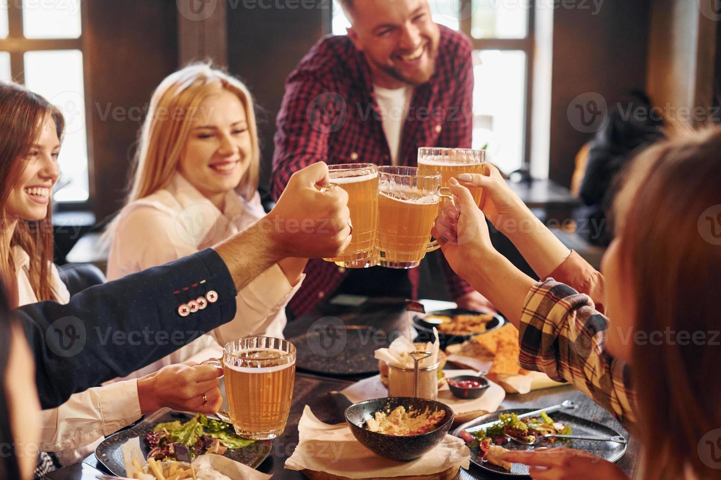 Having fun. Group of young friends sitting together in bar with beer photo