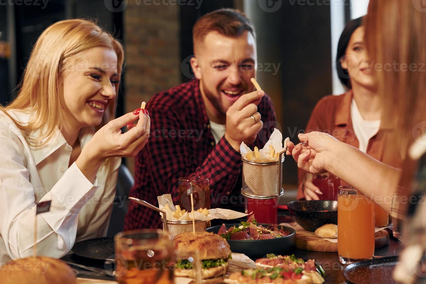 Having conversation. Group of young friends sitting together in bar with beer photo