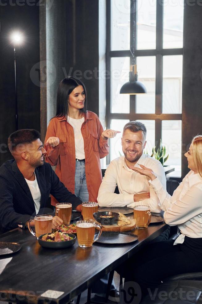 Eating food. Group of young friends sitting together in bar with beer photo
