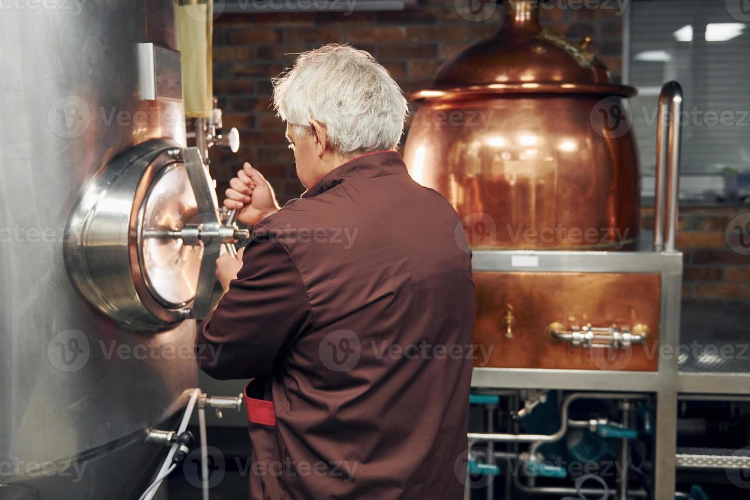 estilo retro. el anciano está parado en el almacenamiento con equipo para cerveza foto