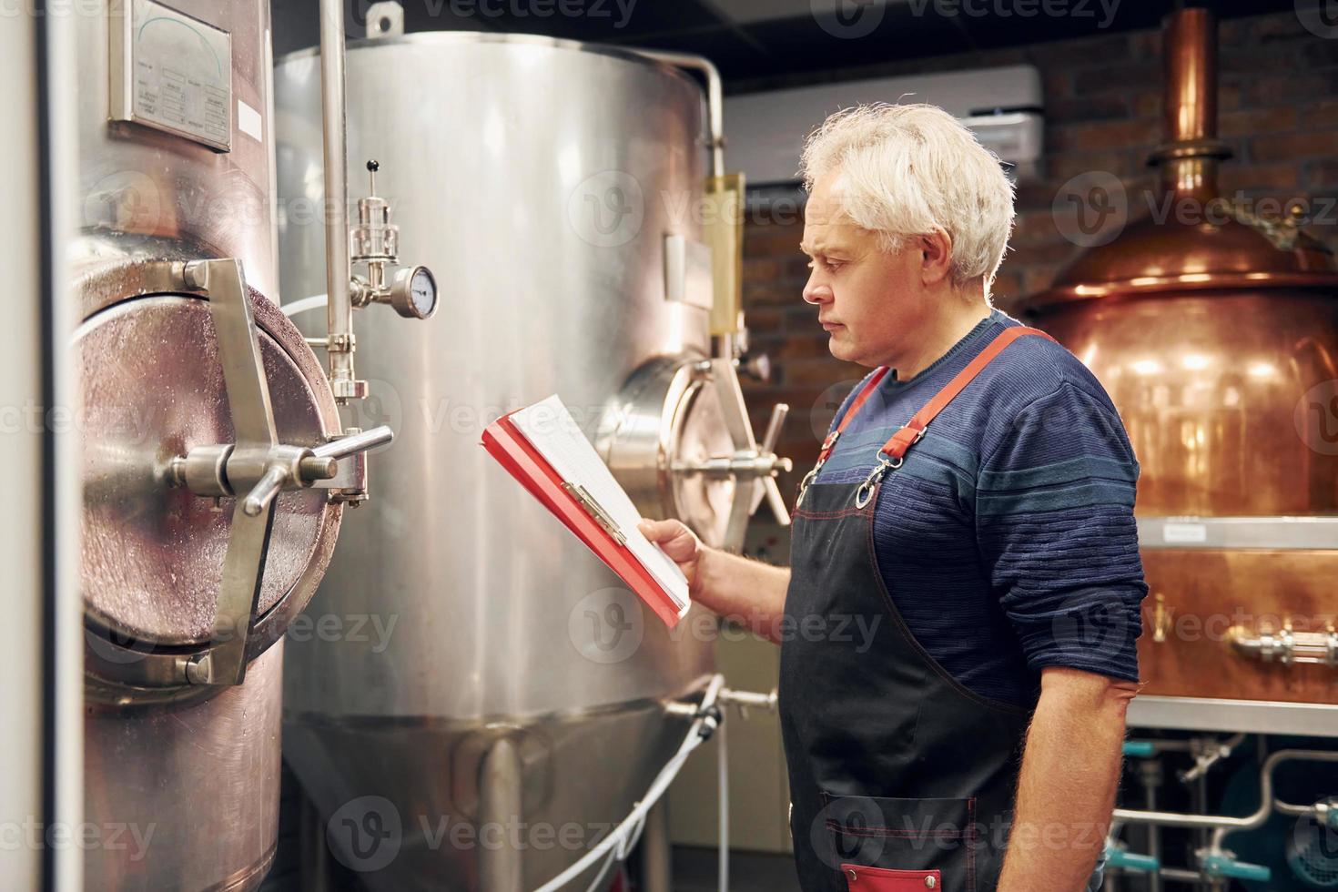 Senior man is standing in the storage with equipment for beer photo