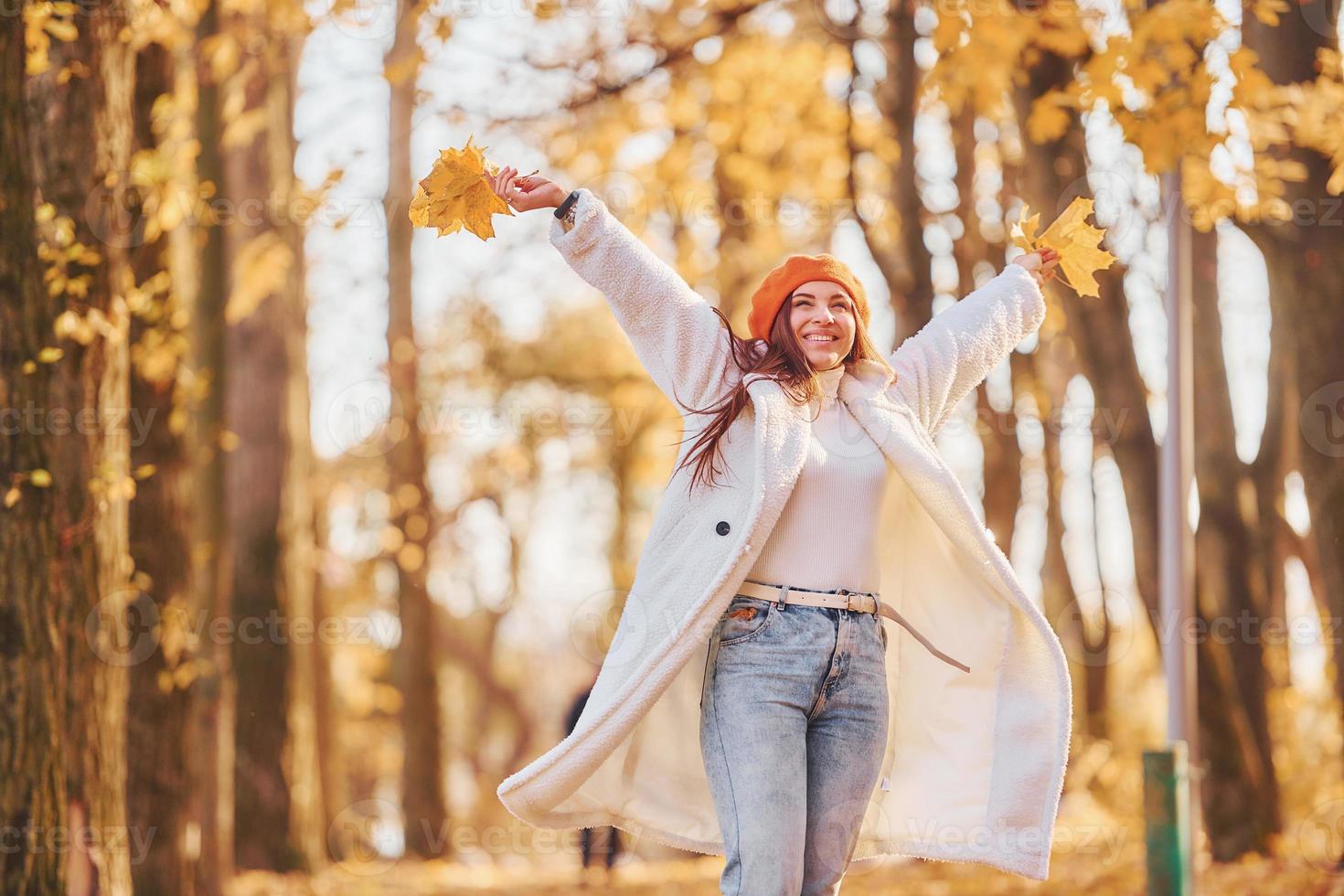 In red beret. Woman in white coat having fun in the autumn park photo