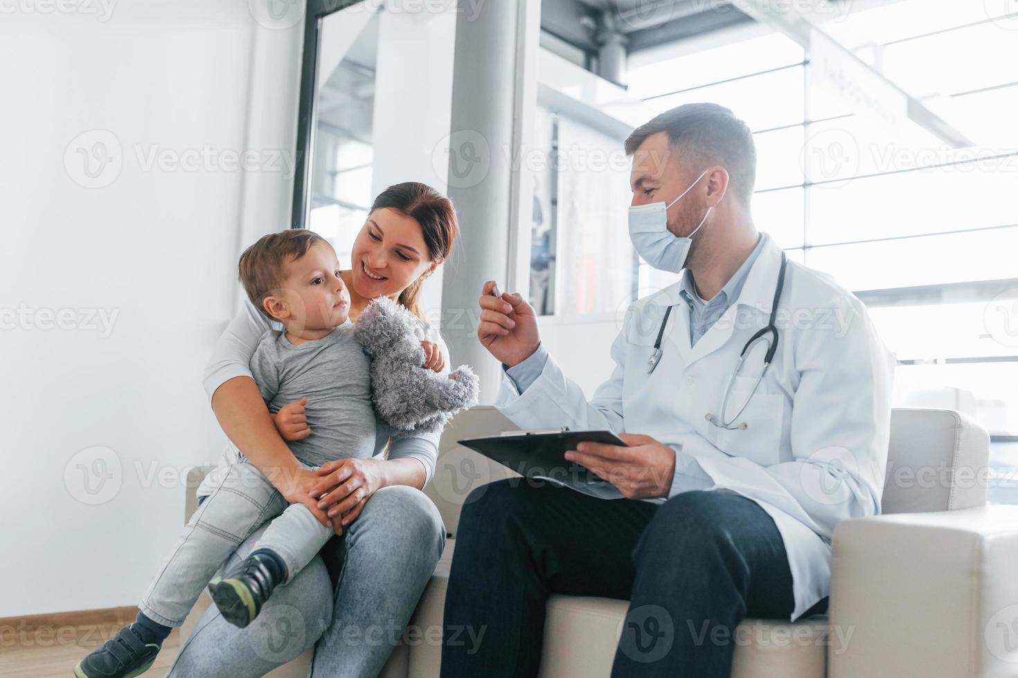 el niño está siendo examinado. dos médicos con batas blancas están en la clínica trabajando juntos foto