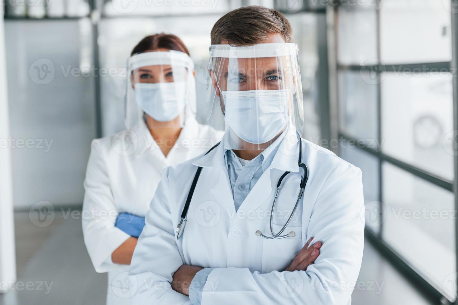 Standing with arms crossed. Two doctors in white coats is in the clinic