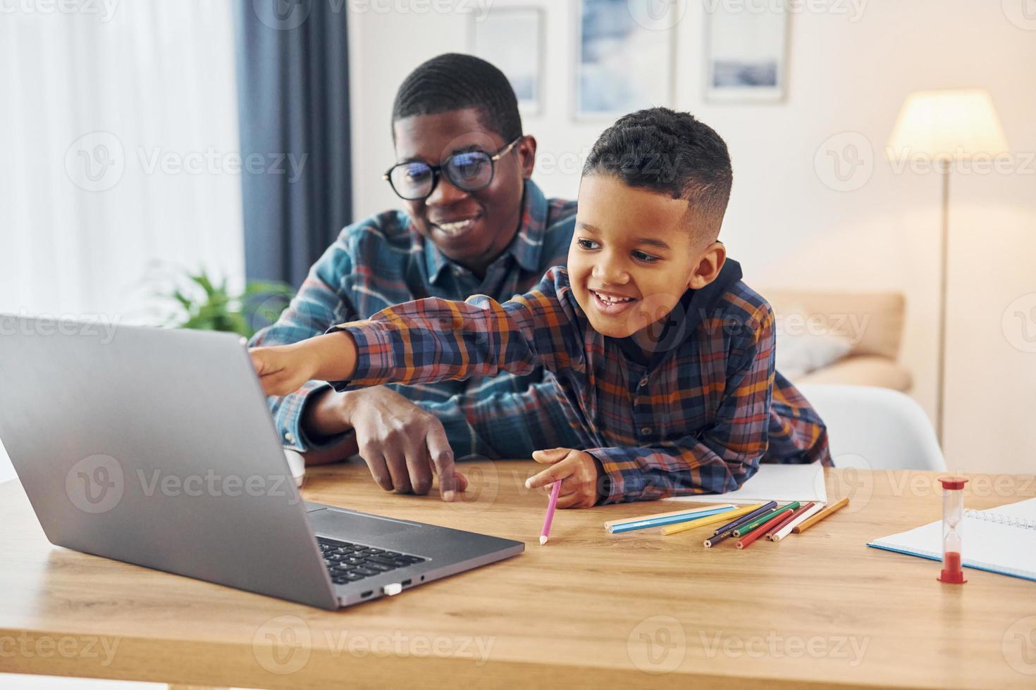 With laptop on table. African american father with his young son at home photo