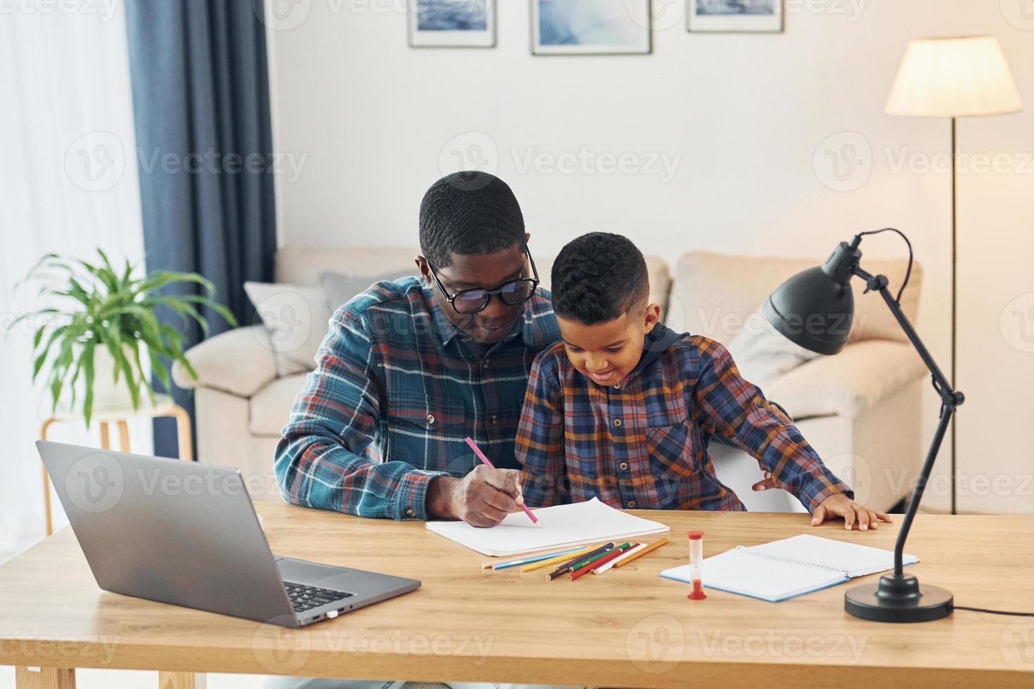 With laptop on table. African american father with his young son at home photo