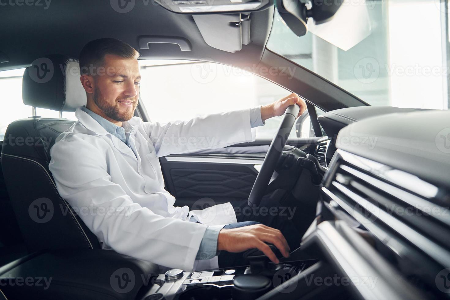 Man in white coat is driving the car photo