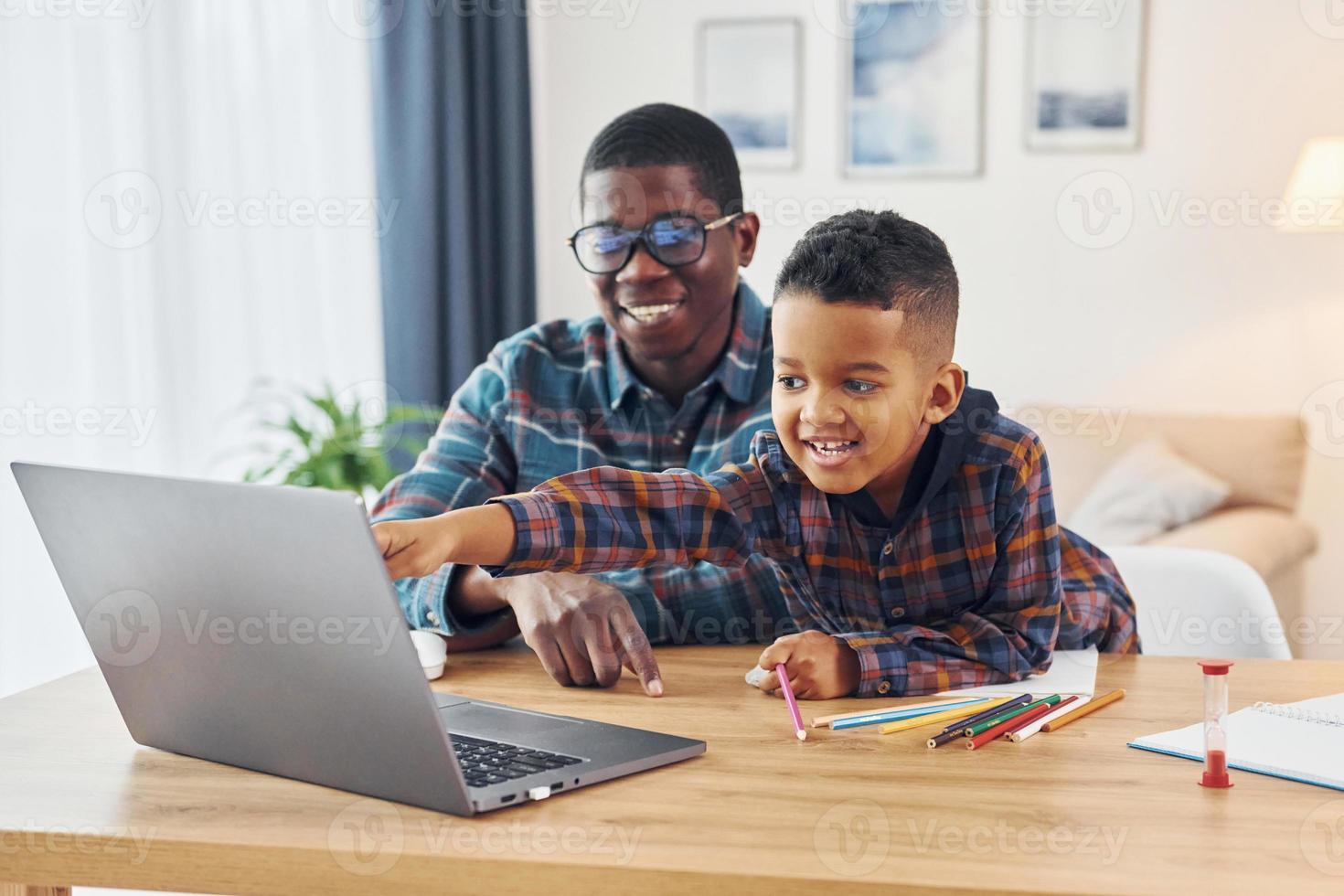 With laptop on table. African american father with his young son at home photo