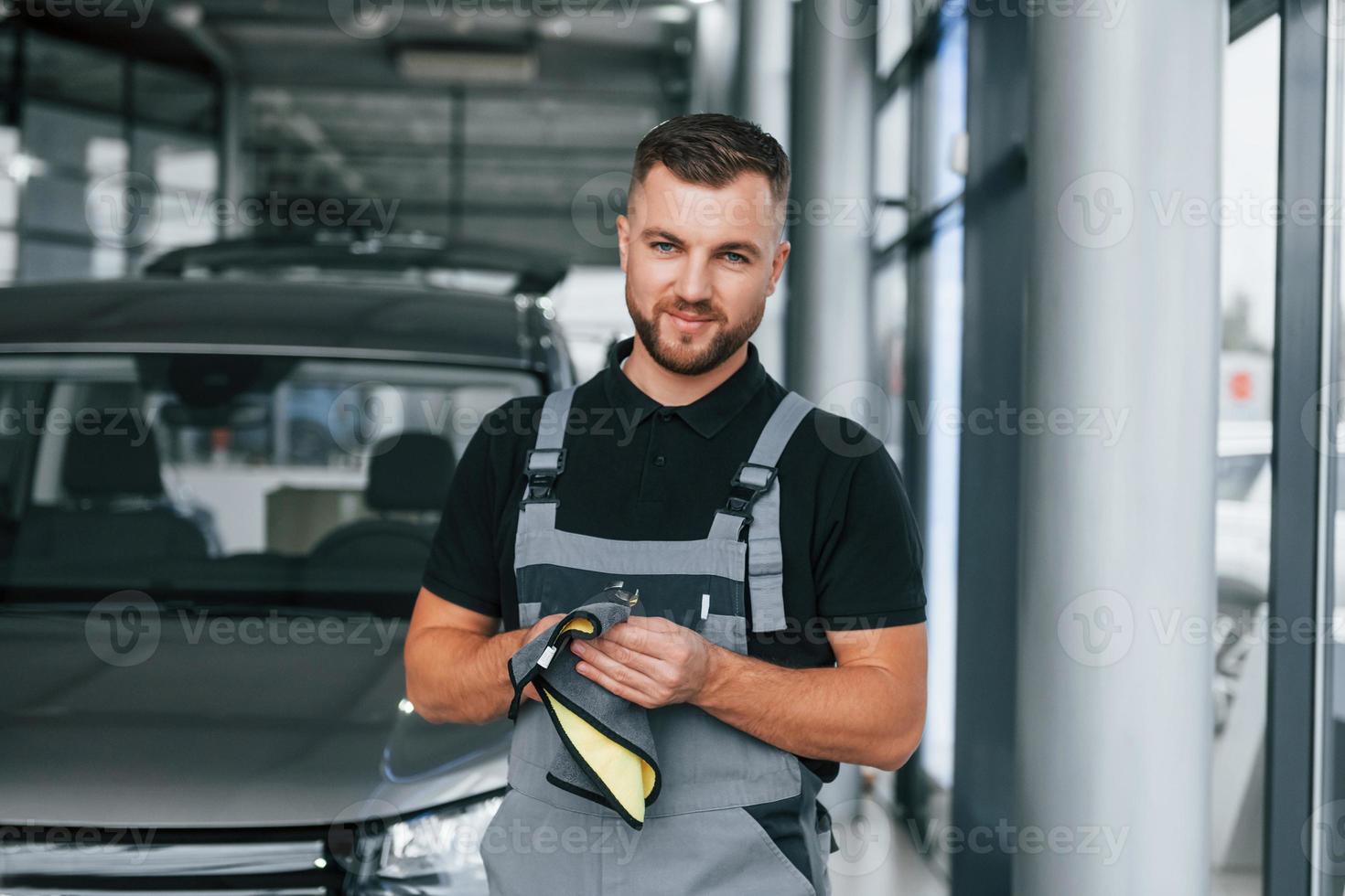 Wiping hands. Man in uniform is working in the autosalon at daytime photo