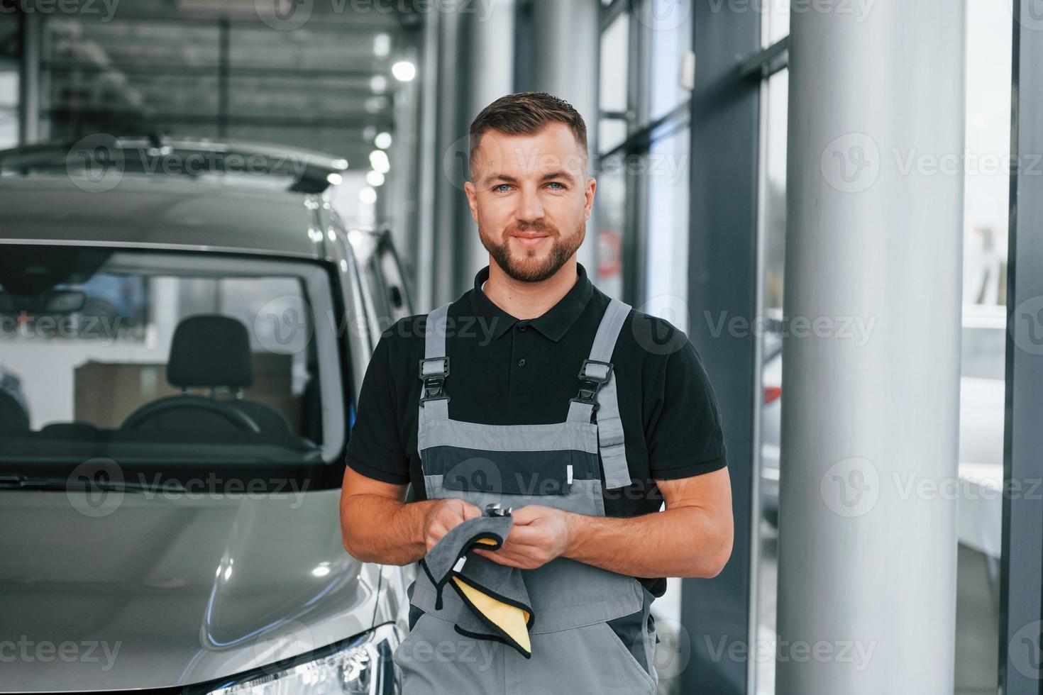 Tools in hands. Man in uniform is working in the autosalon at daytime photo