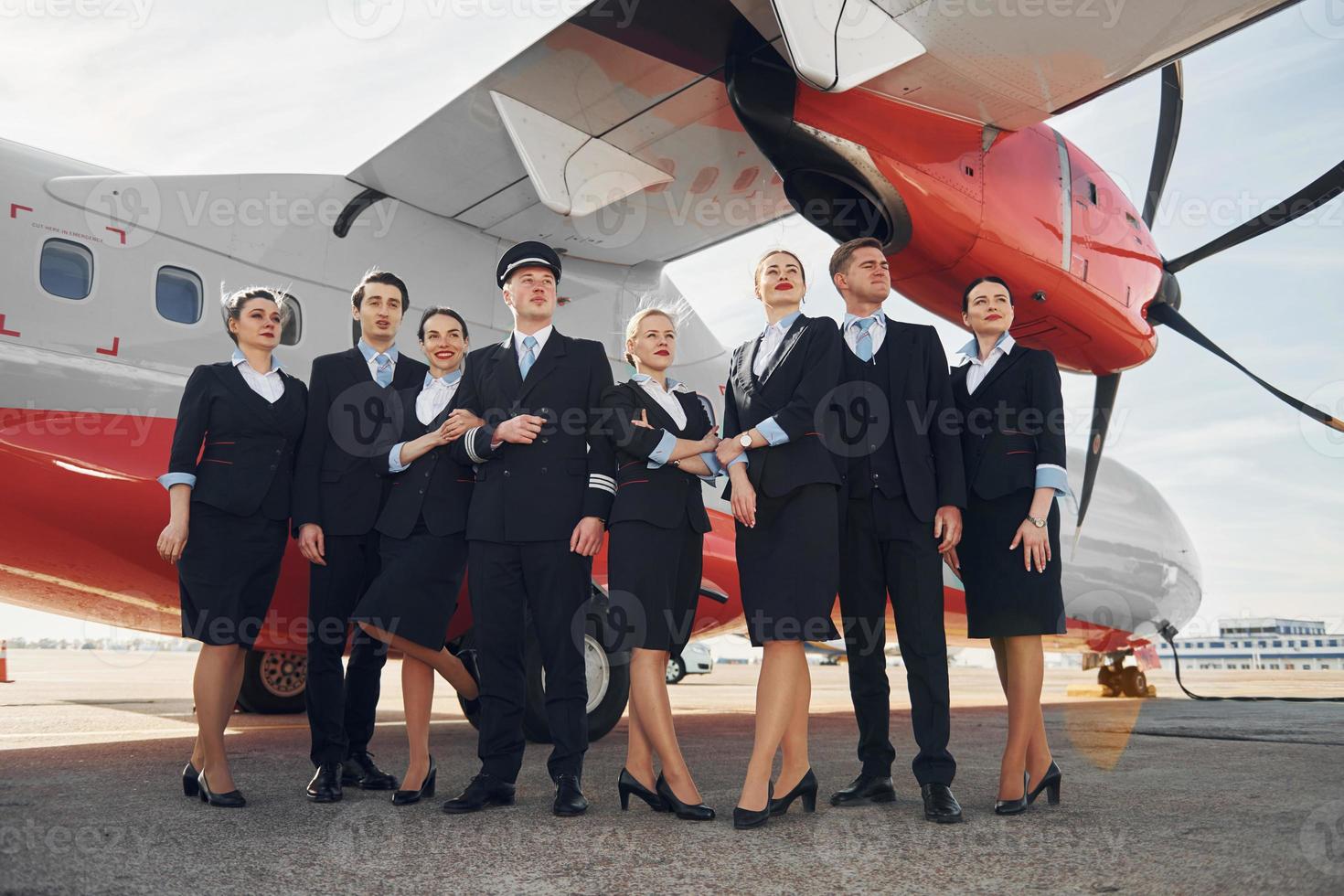 Near plane. Crew of airport workers in formal clothes standing outdoors together photo