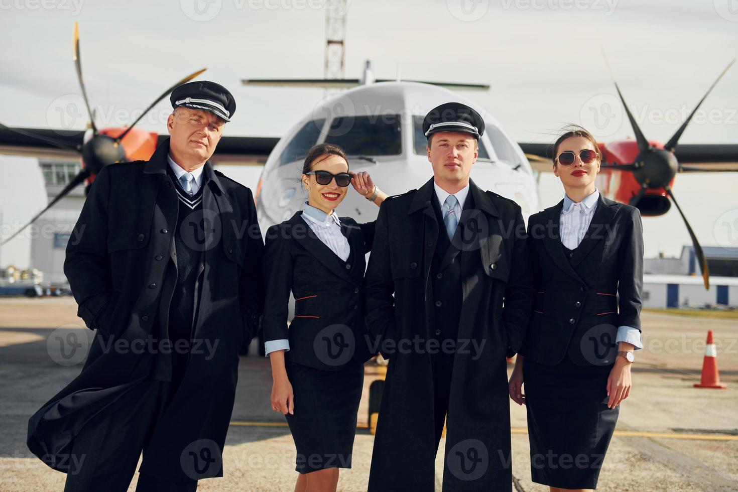Two men and two women. Crew of airport and plane workers in formal clothes standing outdoors together photo