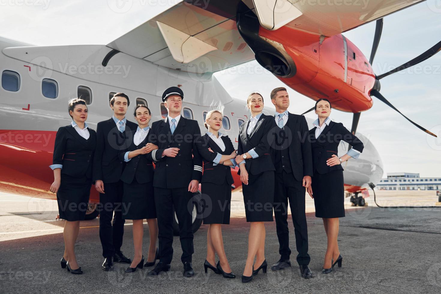 cerca del avión. tripulación de trabajadores del aeropuerto con ropa formal de pie juntos al aire libre foto