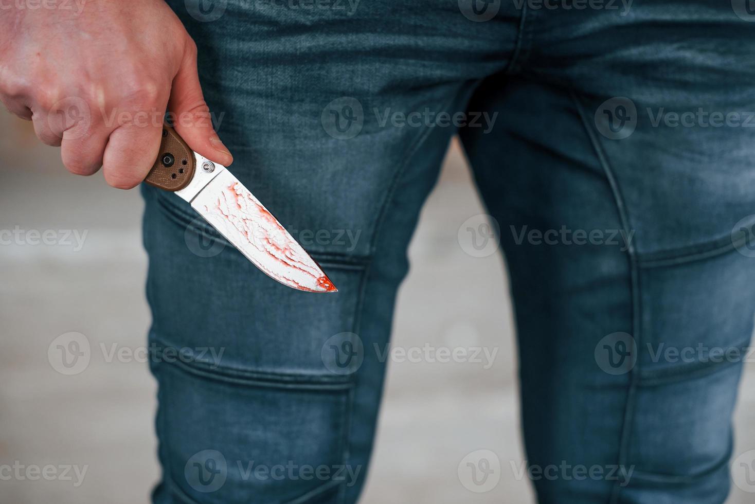 Close up view of killer that standing with knive with blood in hand photo