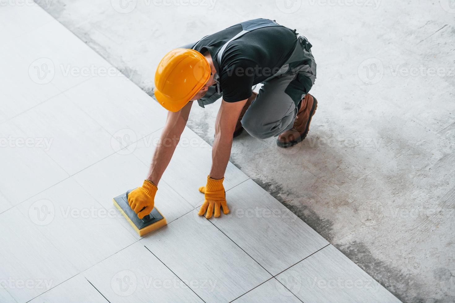 Top view of man in grey uniform that installing plate indoors in modern big office at daytime photo
