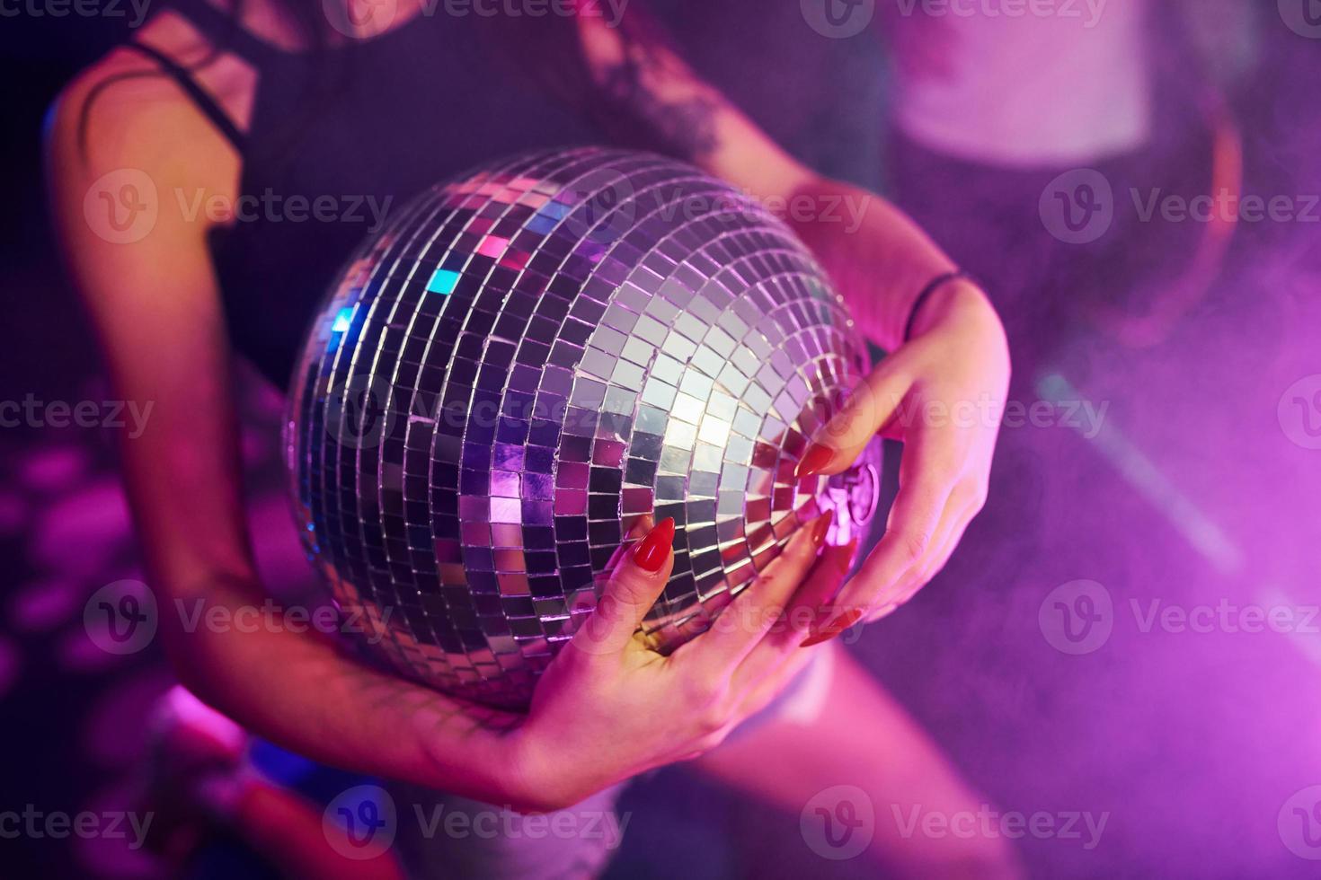 hermosa joven diviértete, bailando en el club nocturno. sosteniendo la pelota de fiesta foto