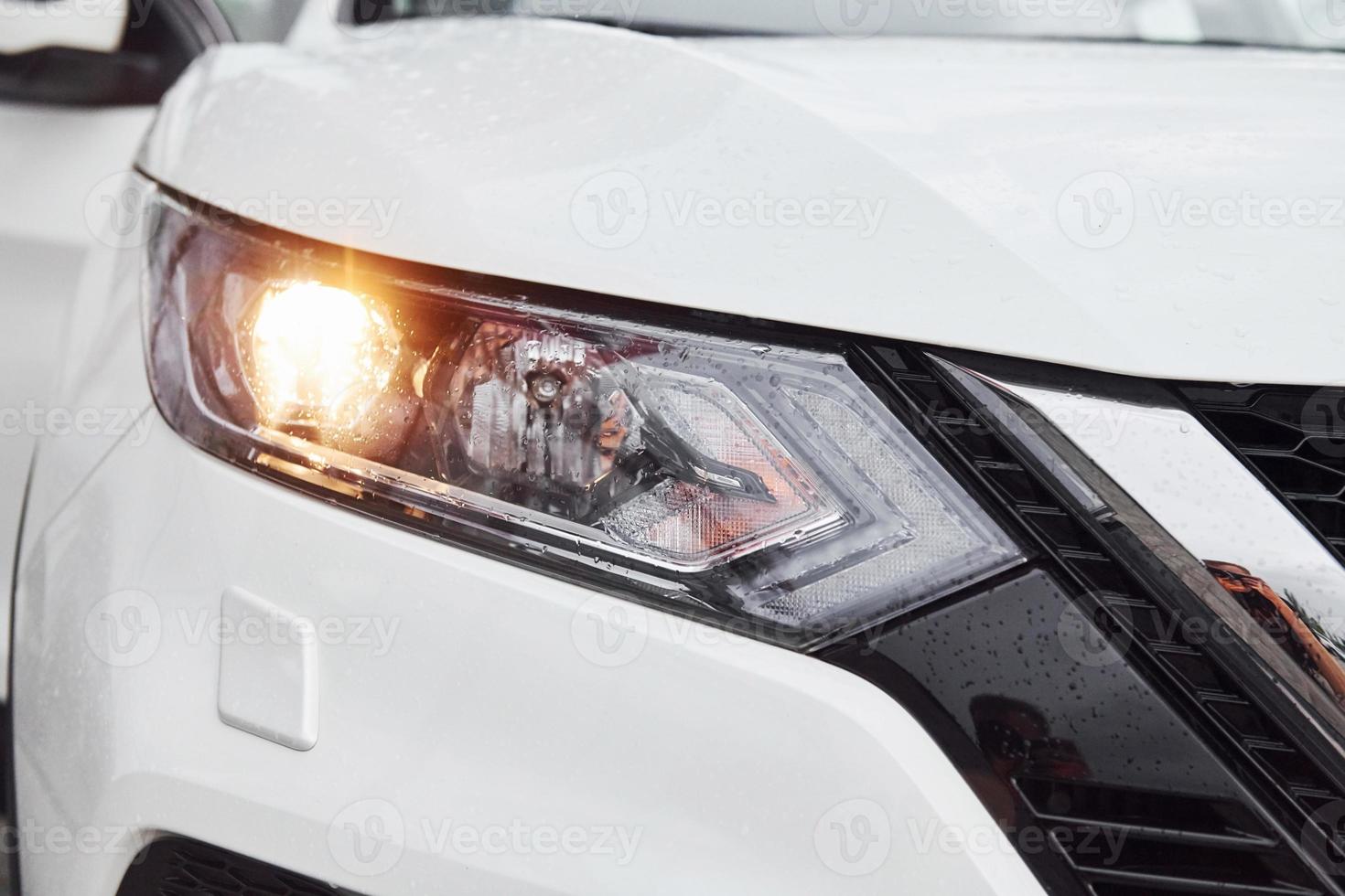 Front particle view of white modern automobile with headlights on photo